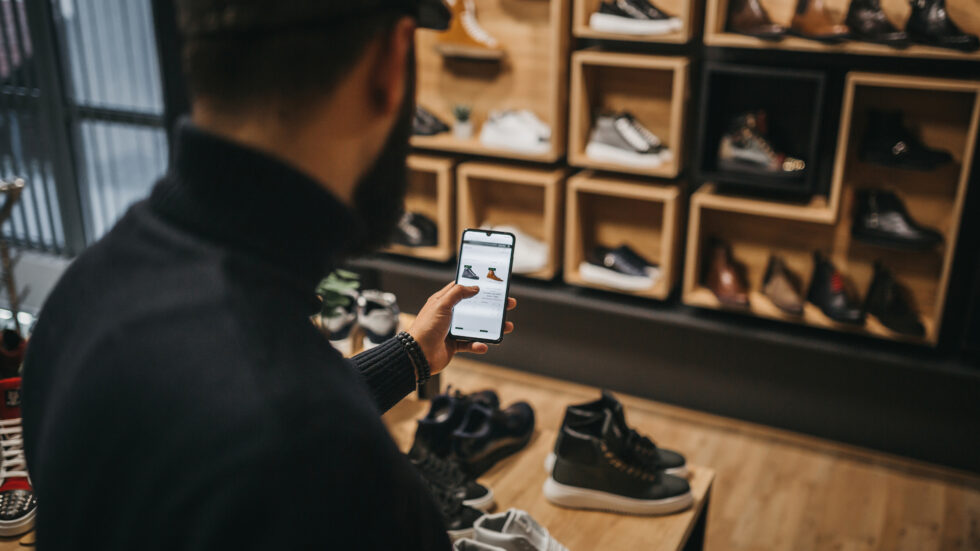 Ein Mann ordert per Smartphone Schuhe.